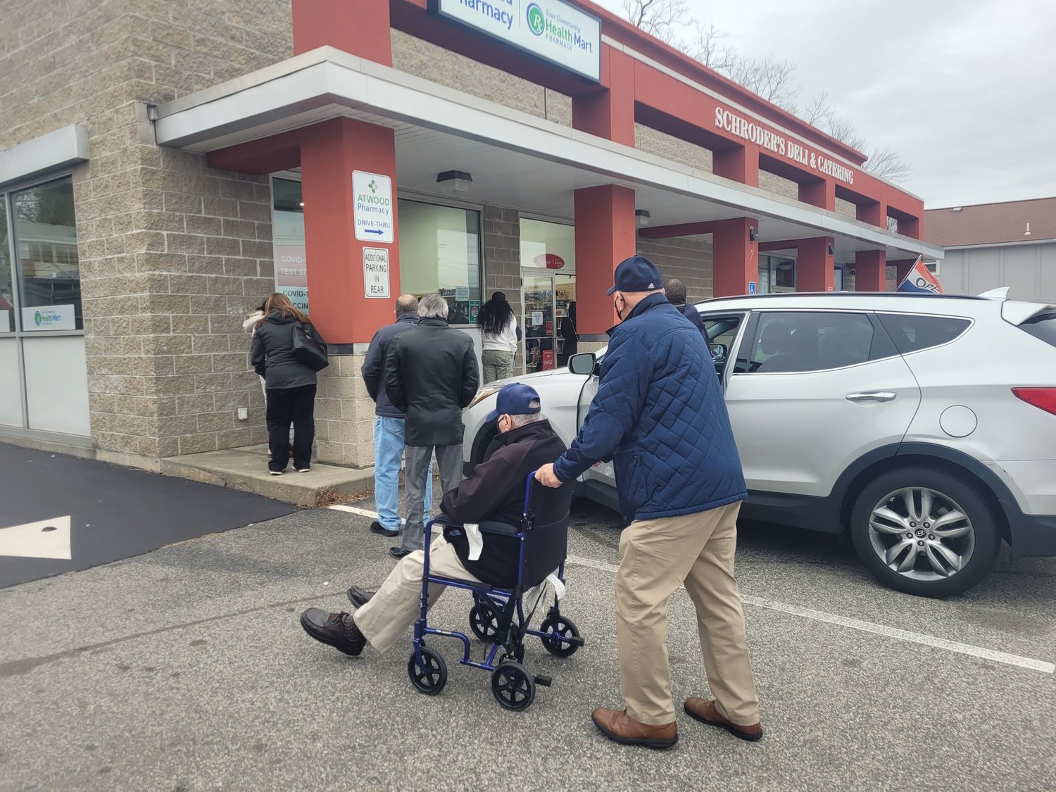 COVID QUEUE: Vincent Palumbo stood behind his brother-in-law Frederick Cardente’s wheelchair Monday, waiting in line for a vaccine booster shot.